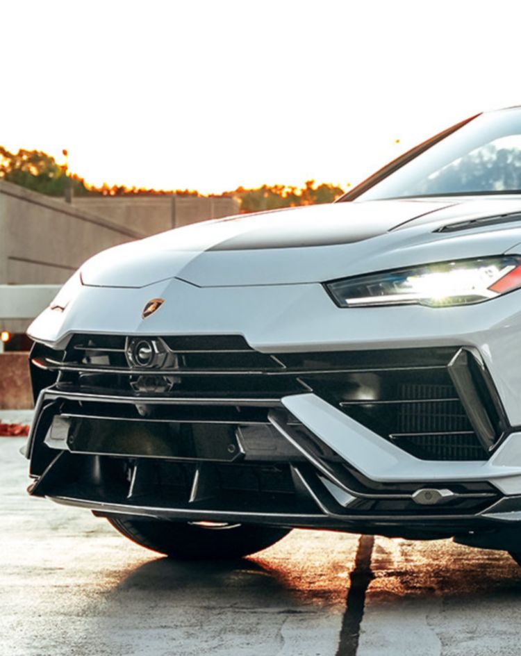 A silver performance SUV parked on a rooftop at sunset, shown from a front three‑quarter angle. 