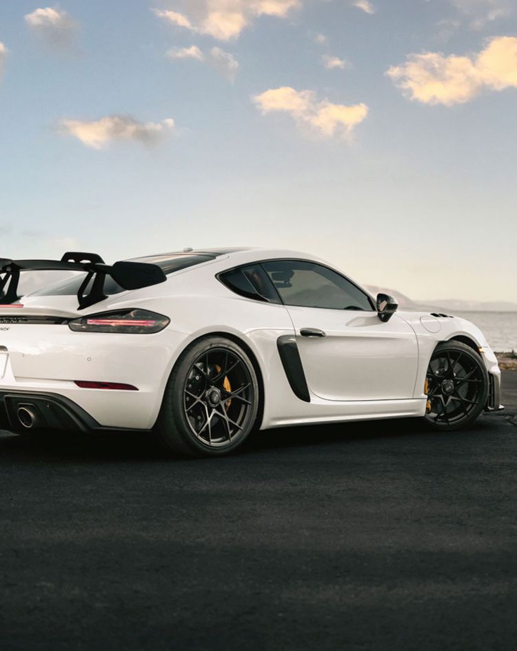 White sports car parked on an open waterfront road at sunset, showcasing a clean exterior finish ideal for enhancing and protecting with automotive paint protection film. 