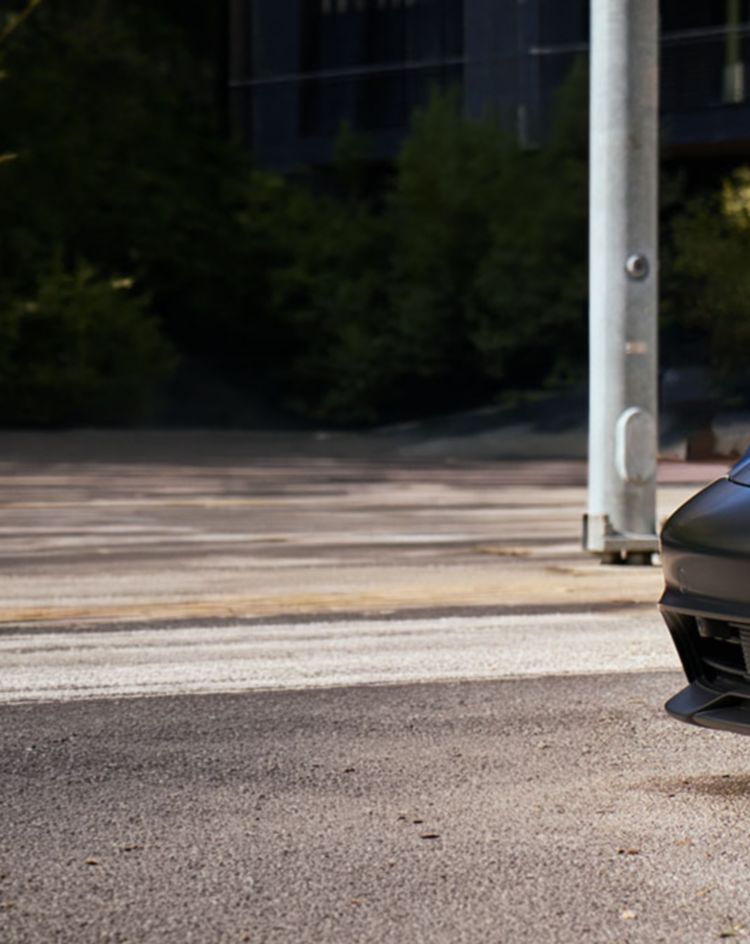 A matte black Porsche Taycan electric sports car parked on a city street 