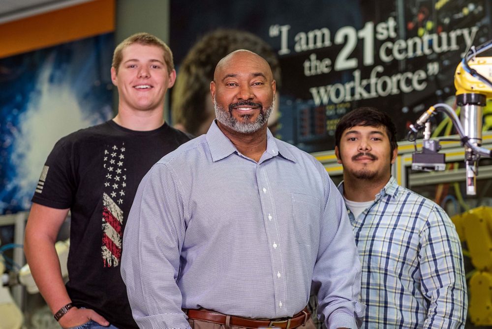 Jeff Fain with two former work-based learning students beside him. 