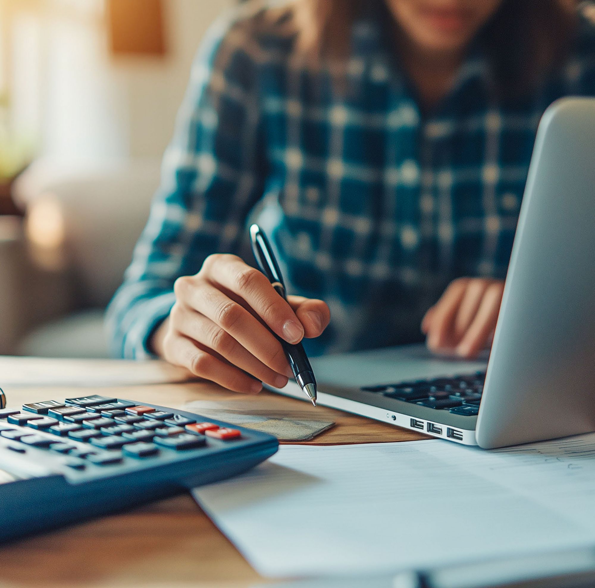 A person holds a pen while working on a laptop. 