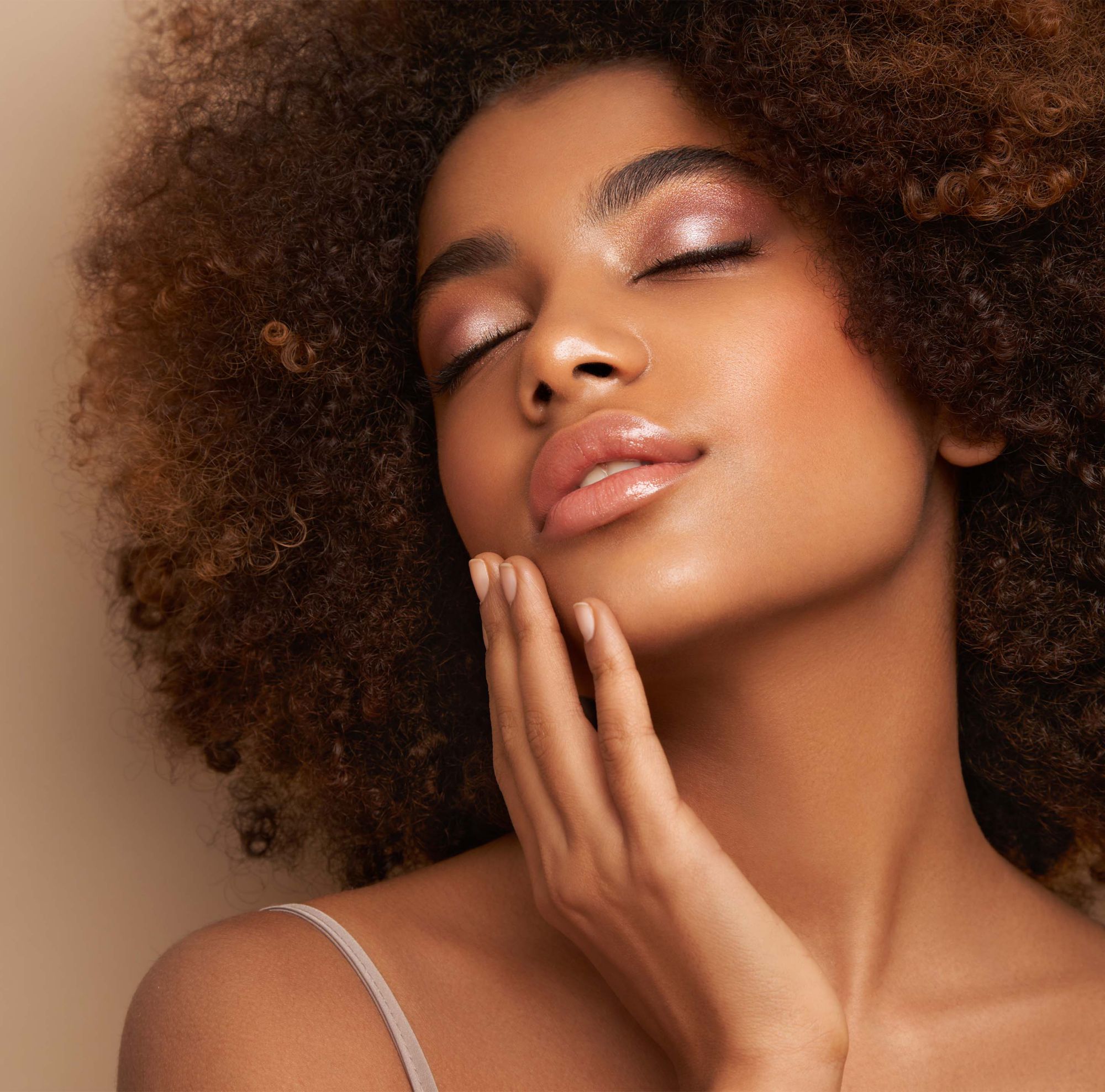 A person with glowing skin touches their face and tilts their head to the sky.   