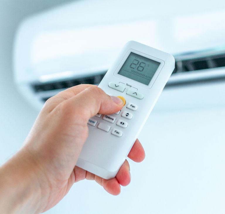 Air conditioner temperature adjustment with remote controller in room at home. 