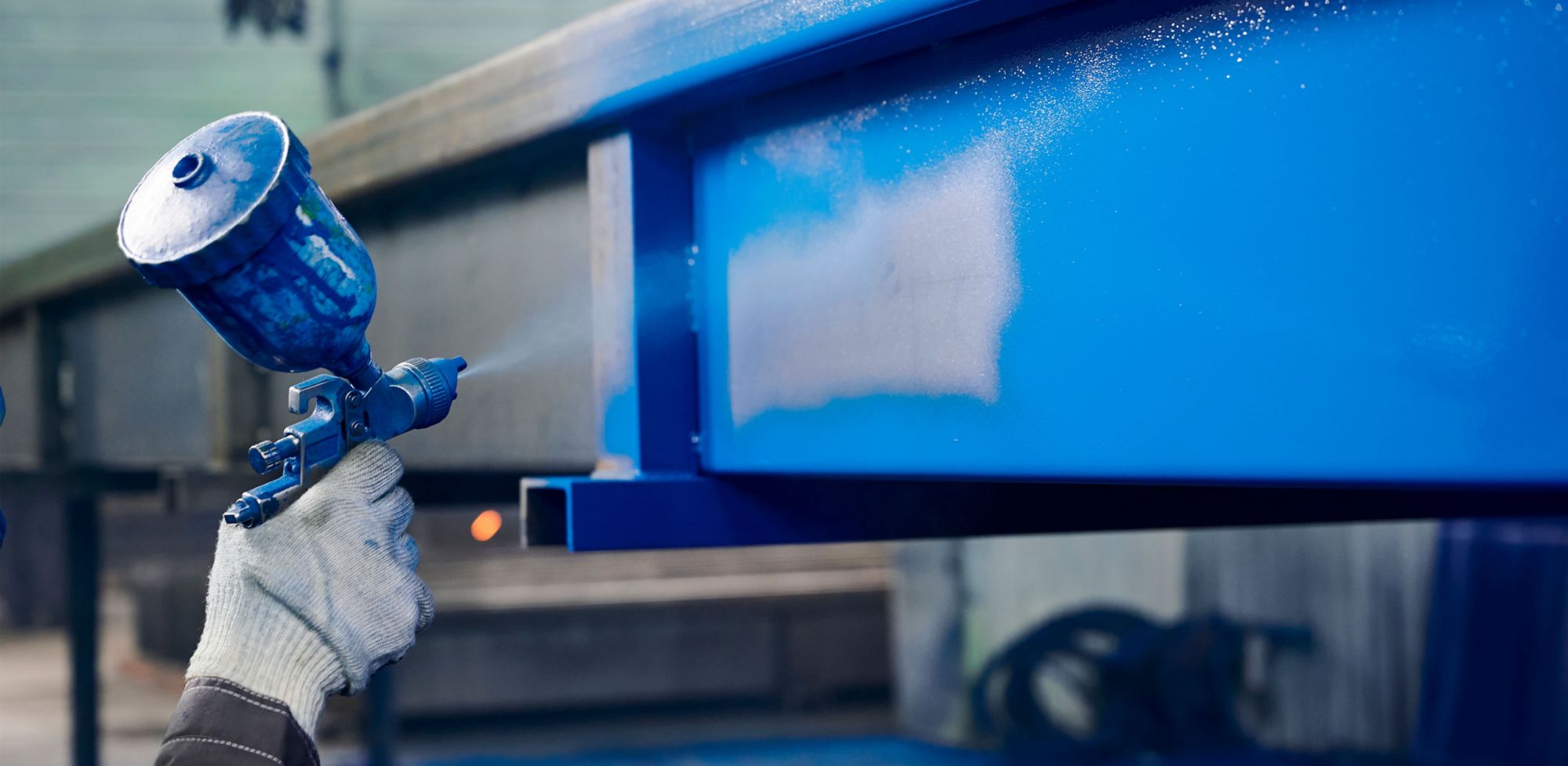 A person spray paints metal blue. 
