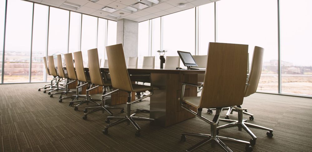 A boardroom table surrounded by glass walls 