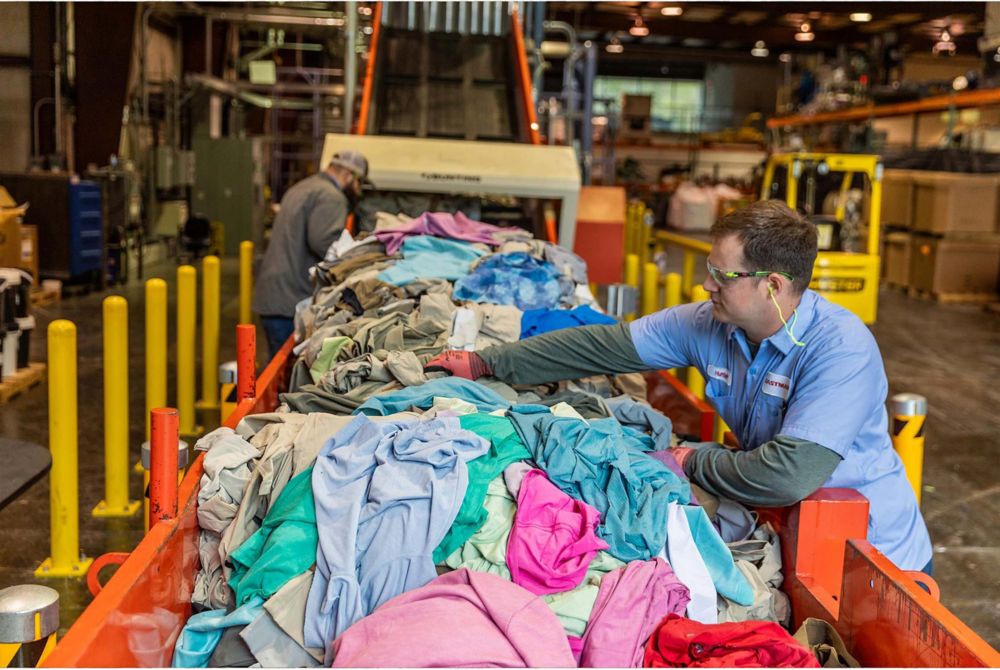 Apparel waste is loaded onto a conveyor belt by Eastman employees 