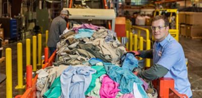 Apparel waste is loaded onto a conveyor belt by Eastman employees 