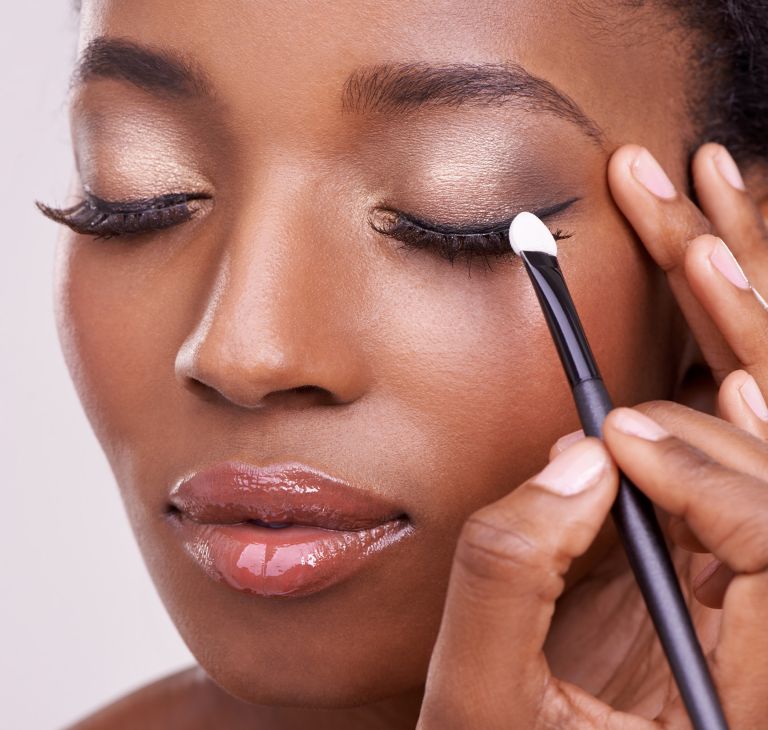 A person applies eye shadow with a makeup brush. 