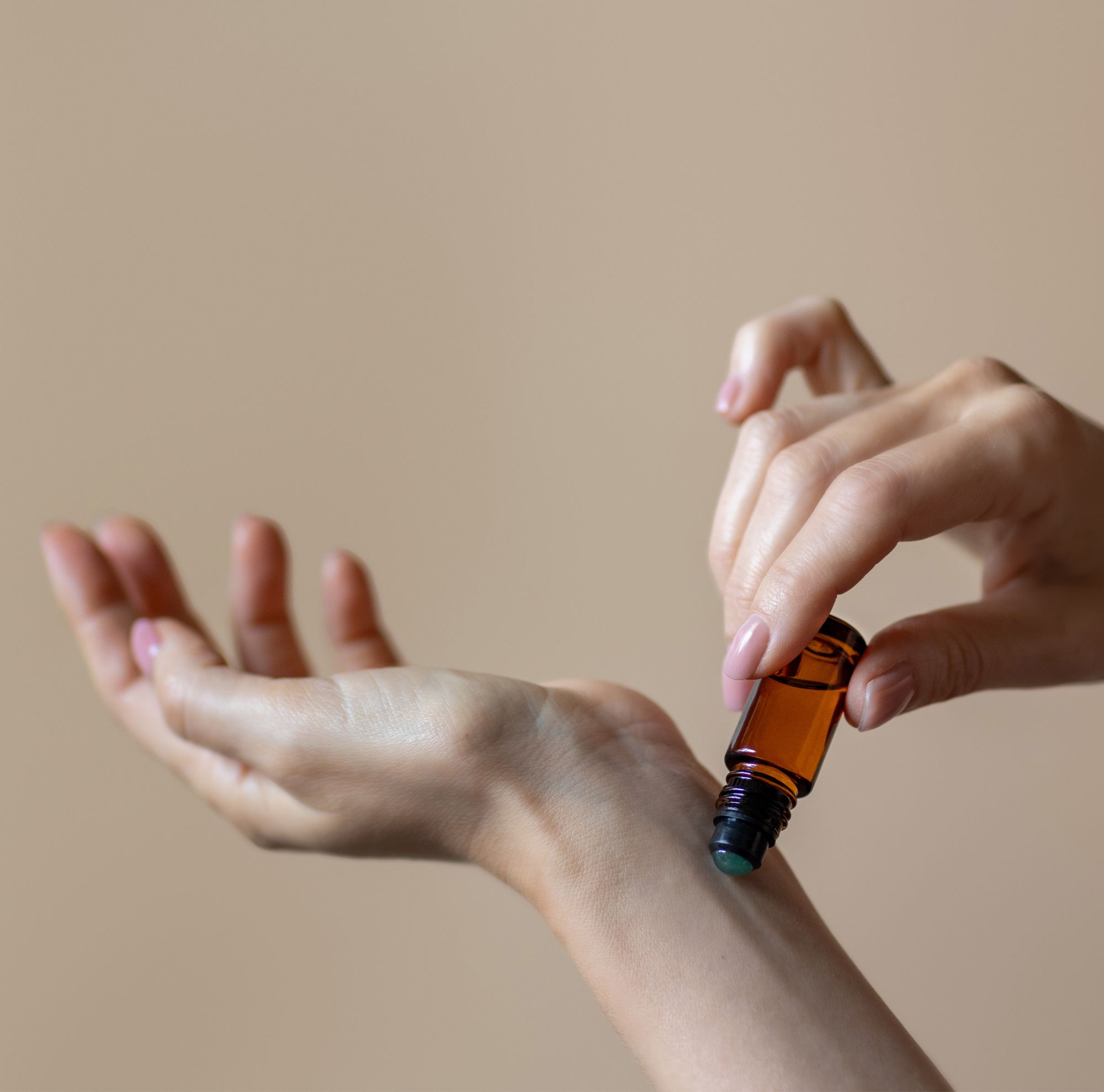 A roller-ball perfume bottle is applied to a wrist.   