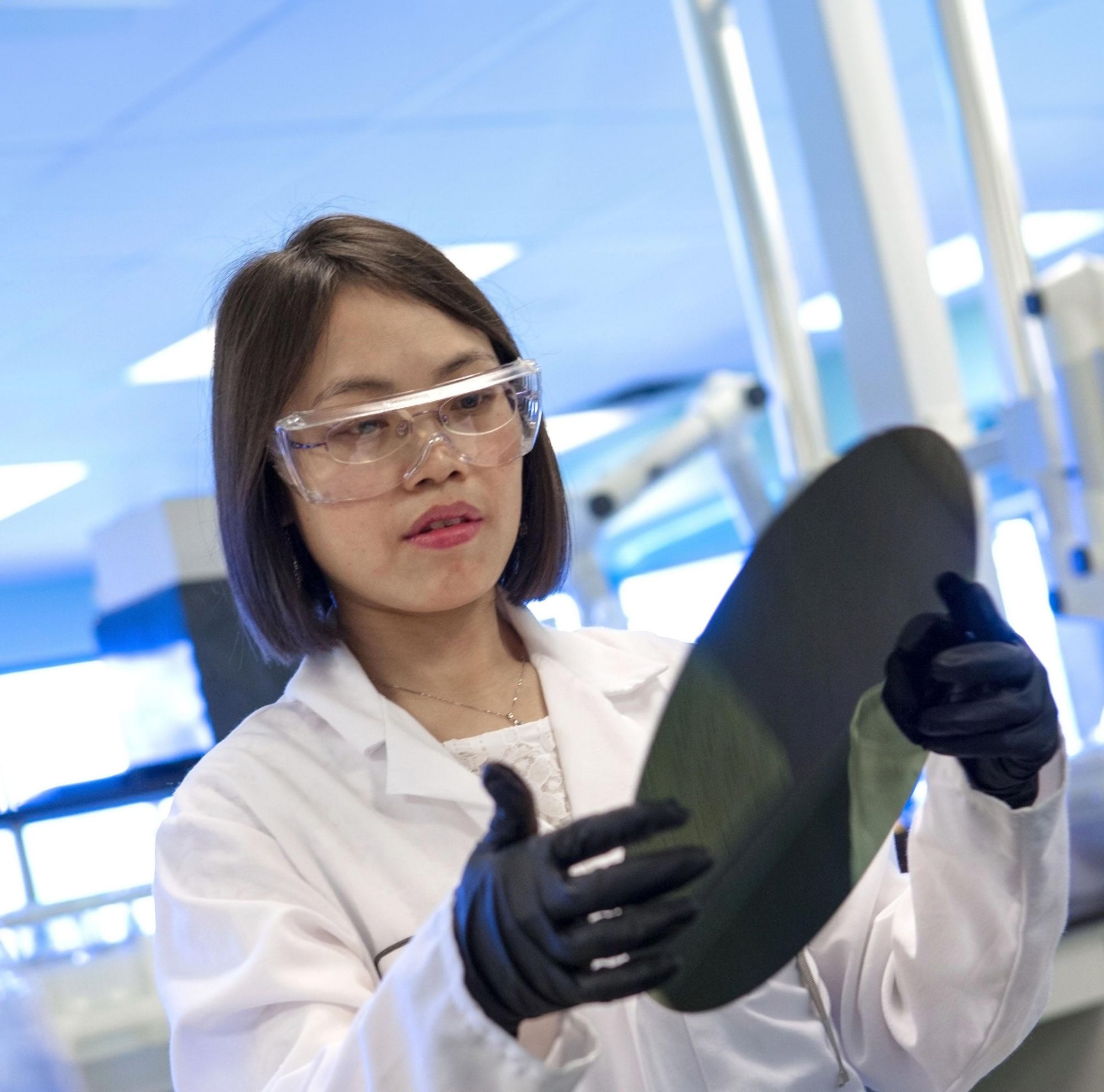 Lab technician inspecting a round object 