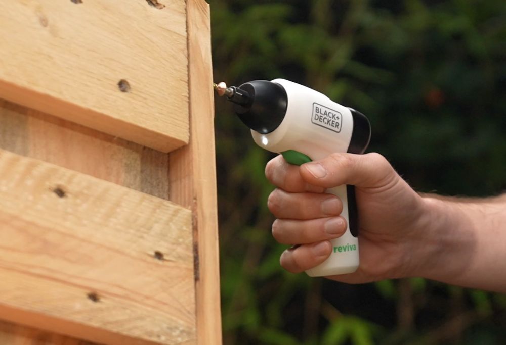 A Black and Decker screwdriver is used to secure wooden boards together.   