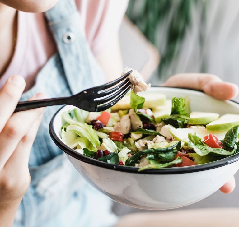 A person eats salad from a bowl using a fork made from Aventa. 