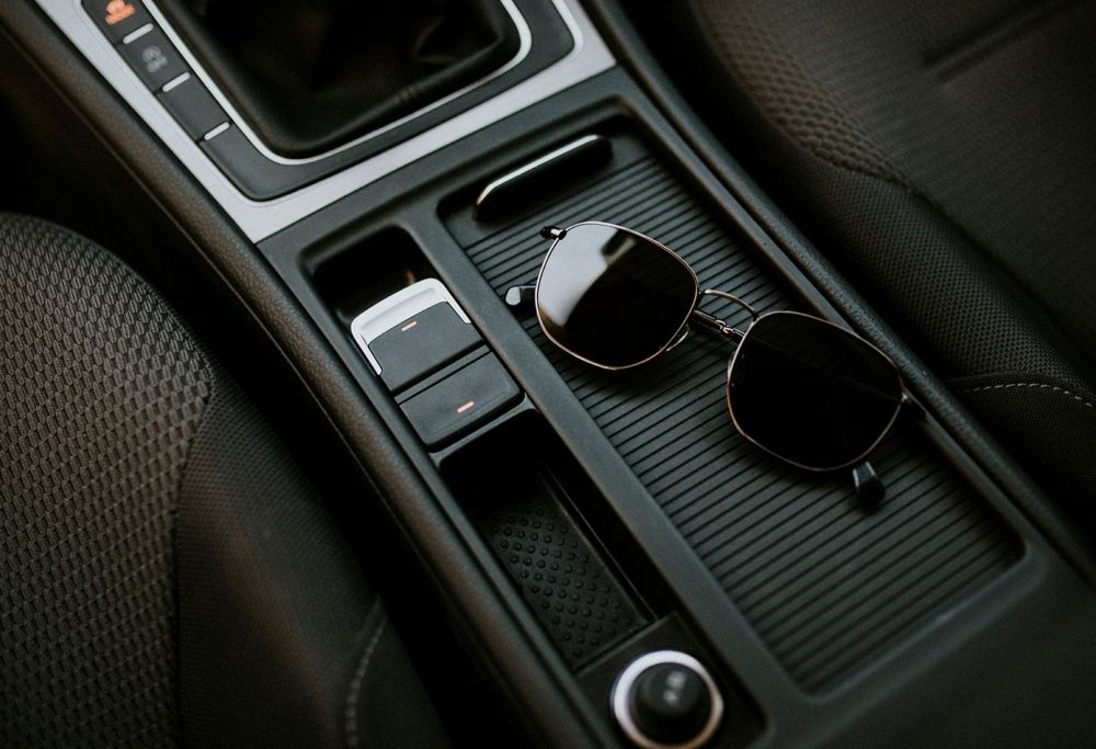 Glasses sit on the middle console in the front of a car. 