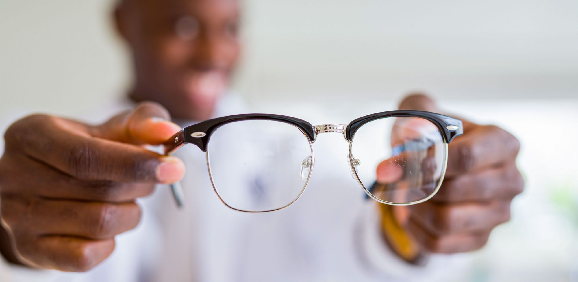 A man holding eyeglasses by its arms. 