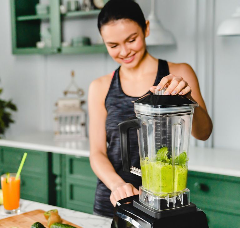 A person uses a blender for a green smoothie. 
