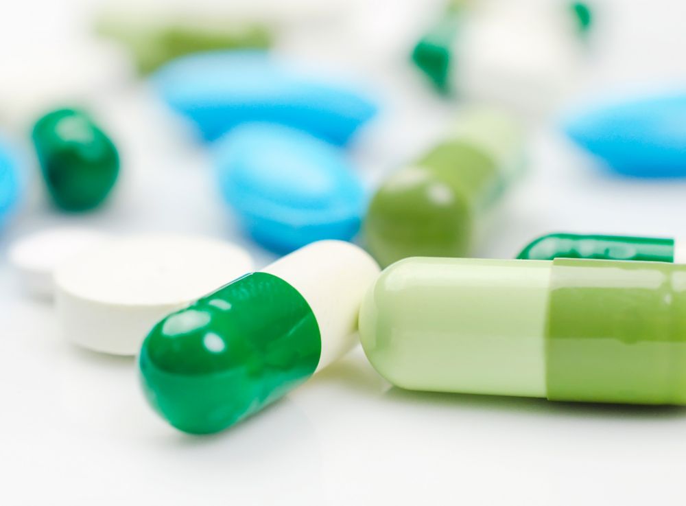 Pills of different shapes and colors on a table. 