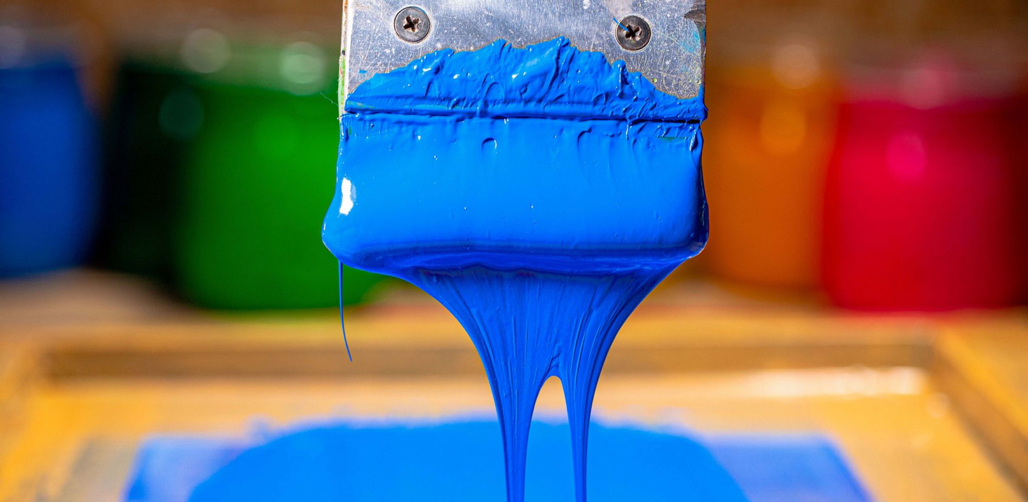 A closeup of blue paint dripping from a brush. 