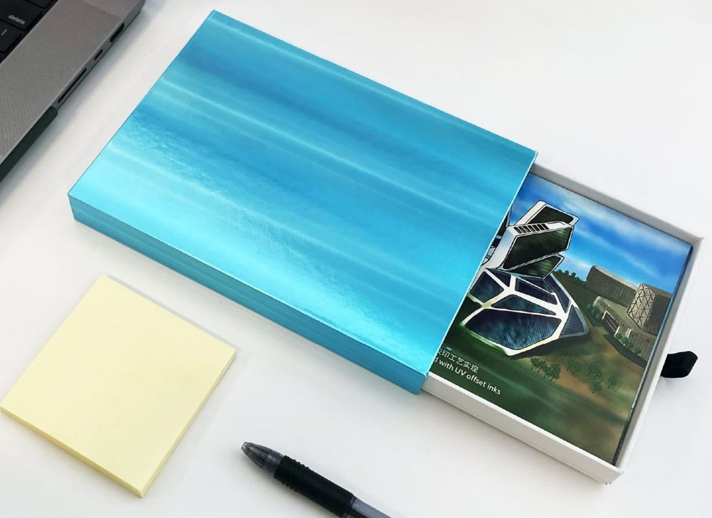 A stack of printed cards inside a partially open display box. 