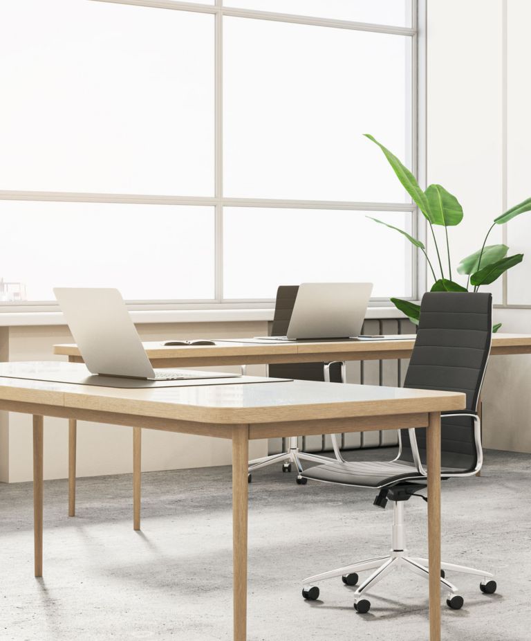 A bright office space with two desks, two laptops and two chair 