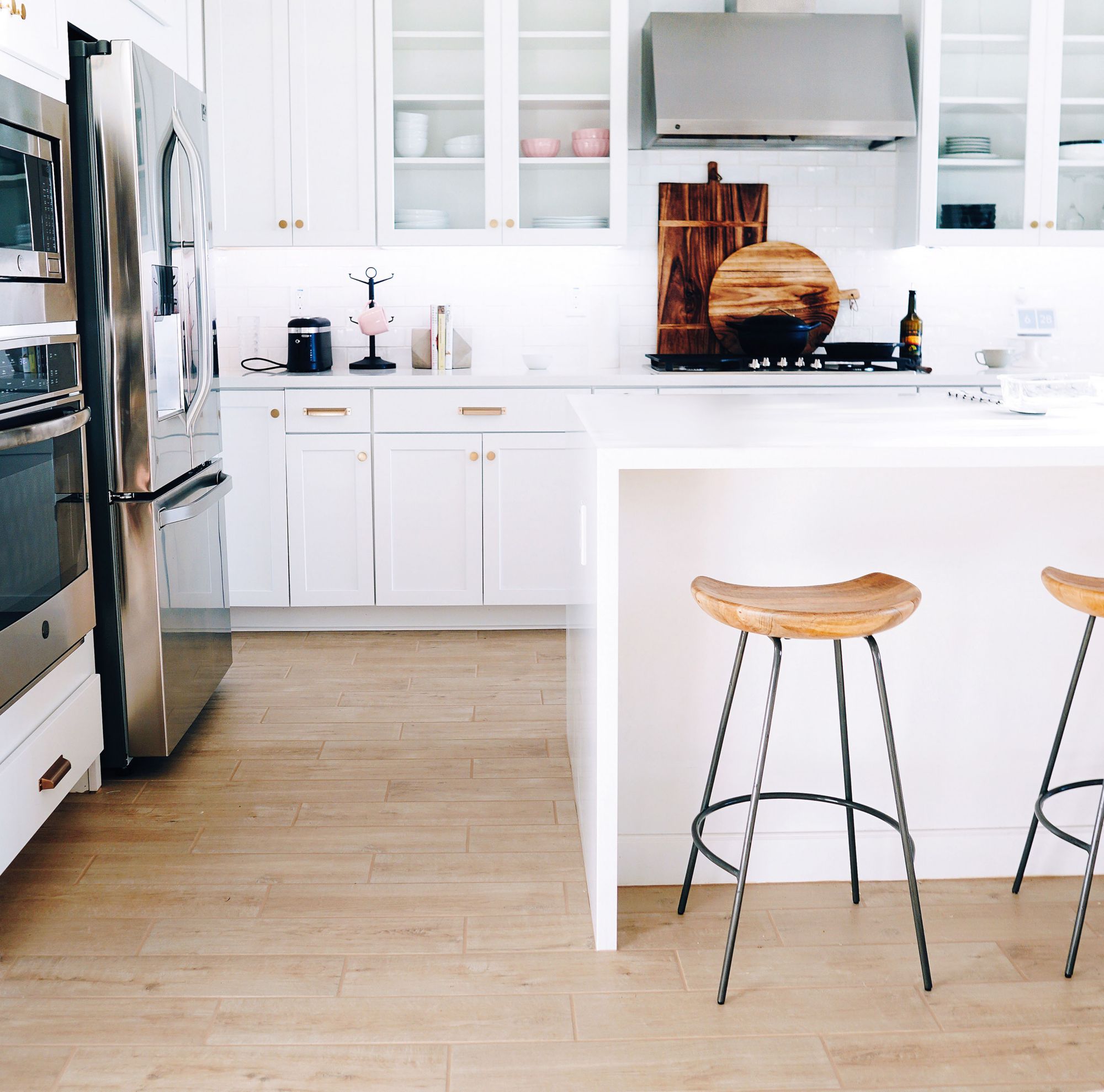 A refrigerator and oven in a kitchen, with stools at an island. 
