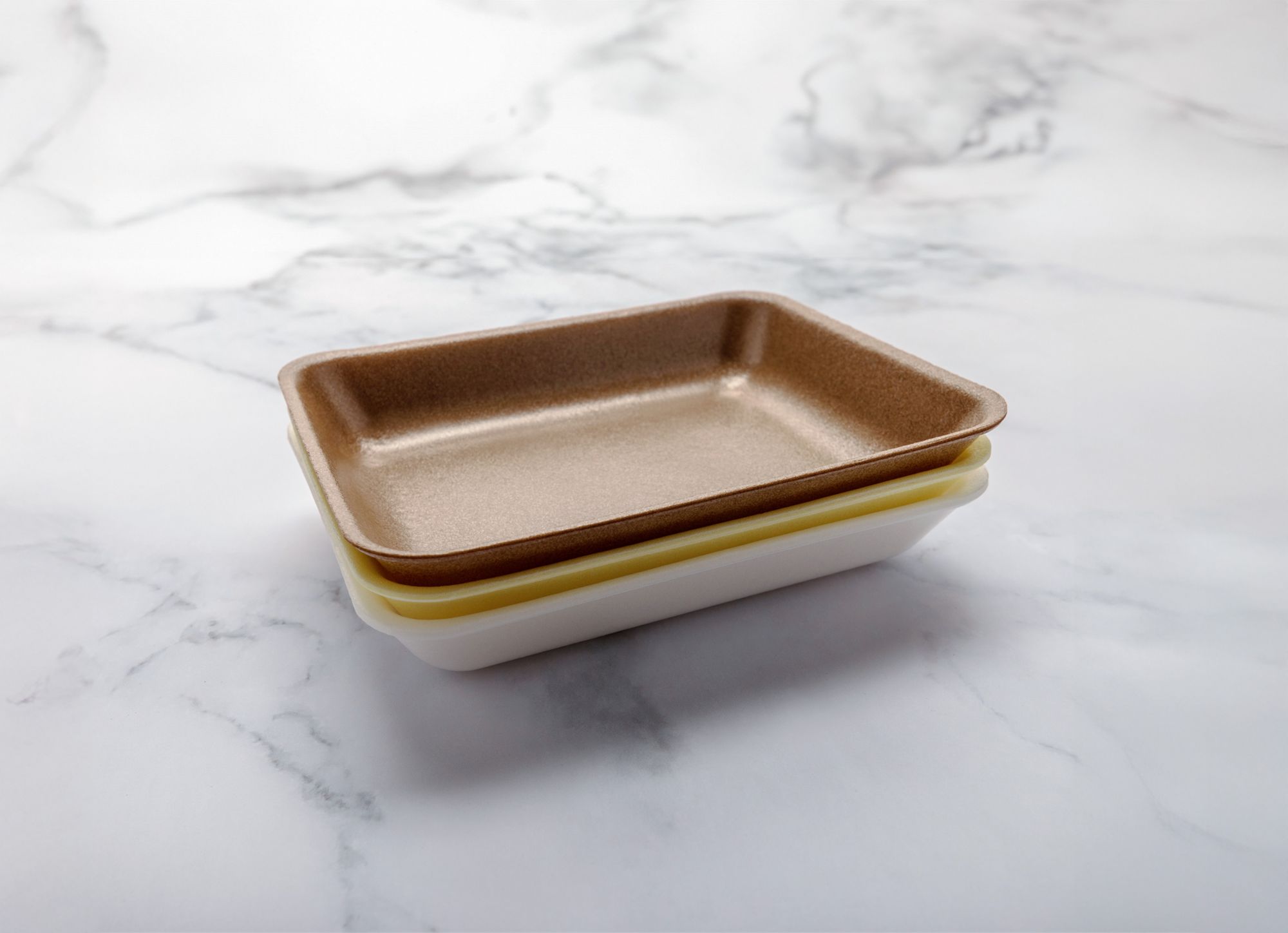 Brown, yellow and white protein trays are stacked together. 