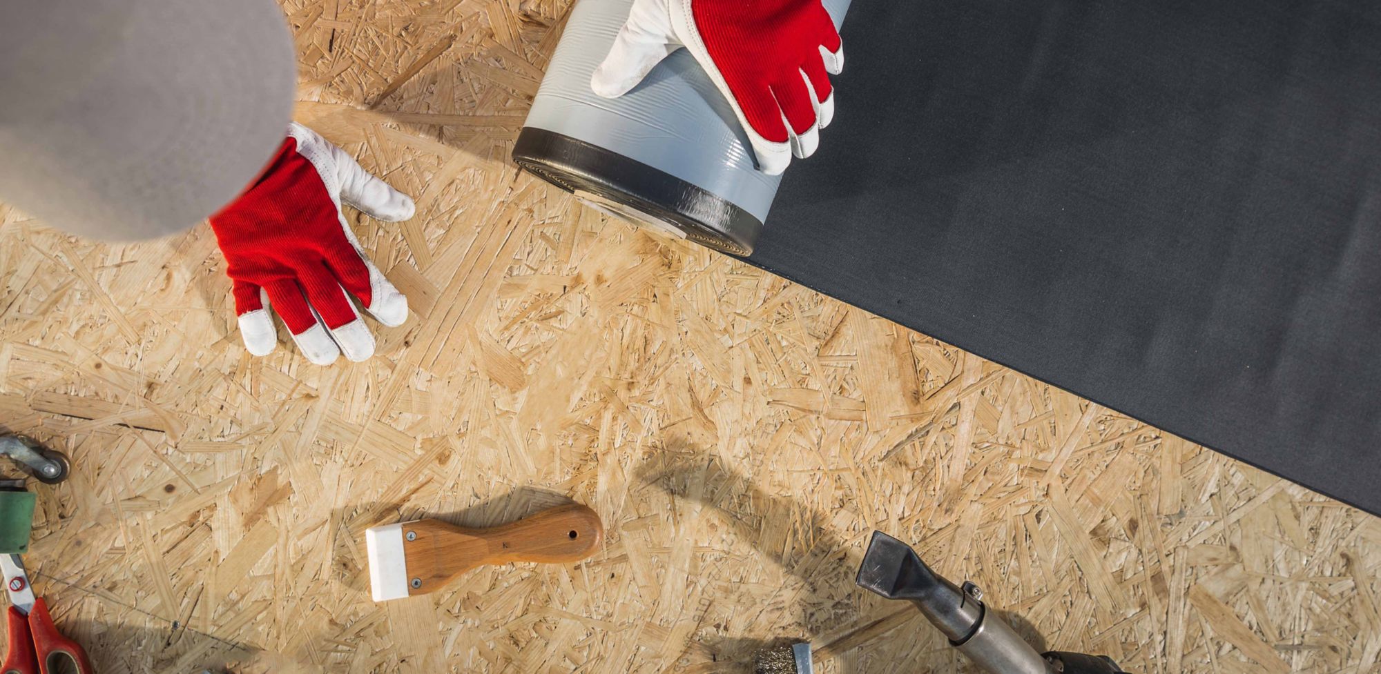 A person rolls covering over a wood surface. 