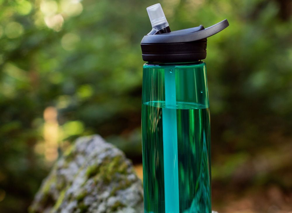 CamelBak water bottle balanced on a mossy rock. 