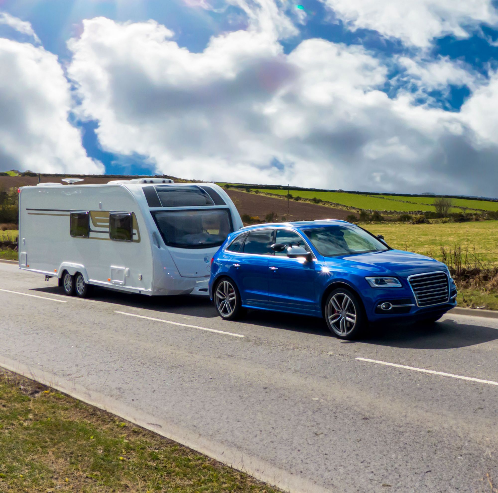 A blue SUV towing a travel trailer. 