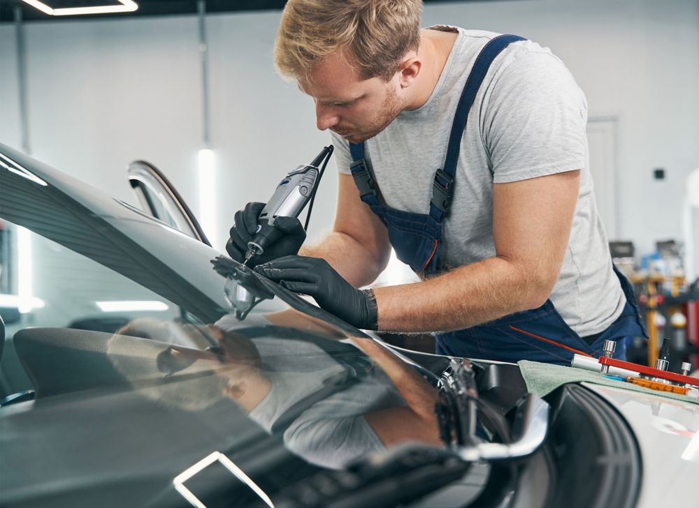 Auto glass repair technician fixing a car windshield. 