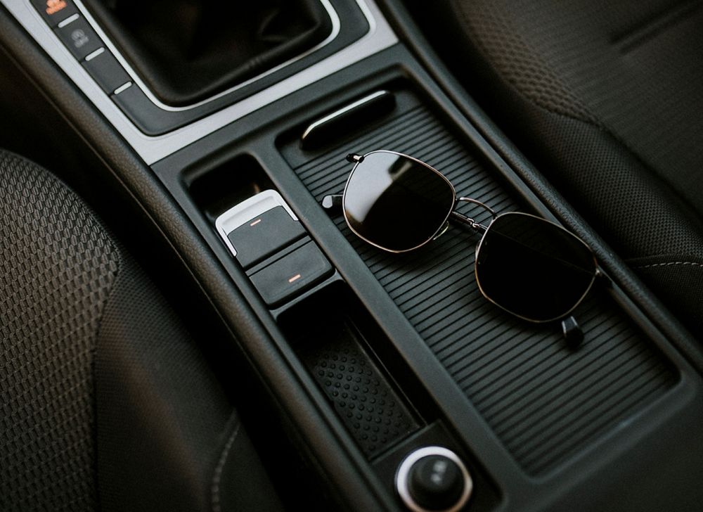 Glasses sit on the middle console in the front of a car. 