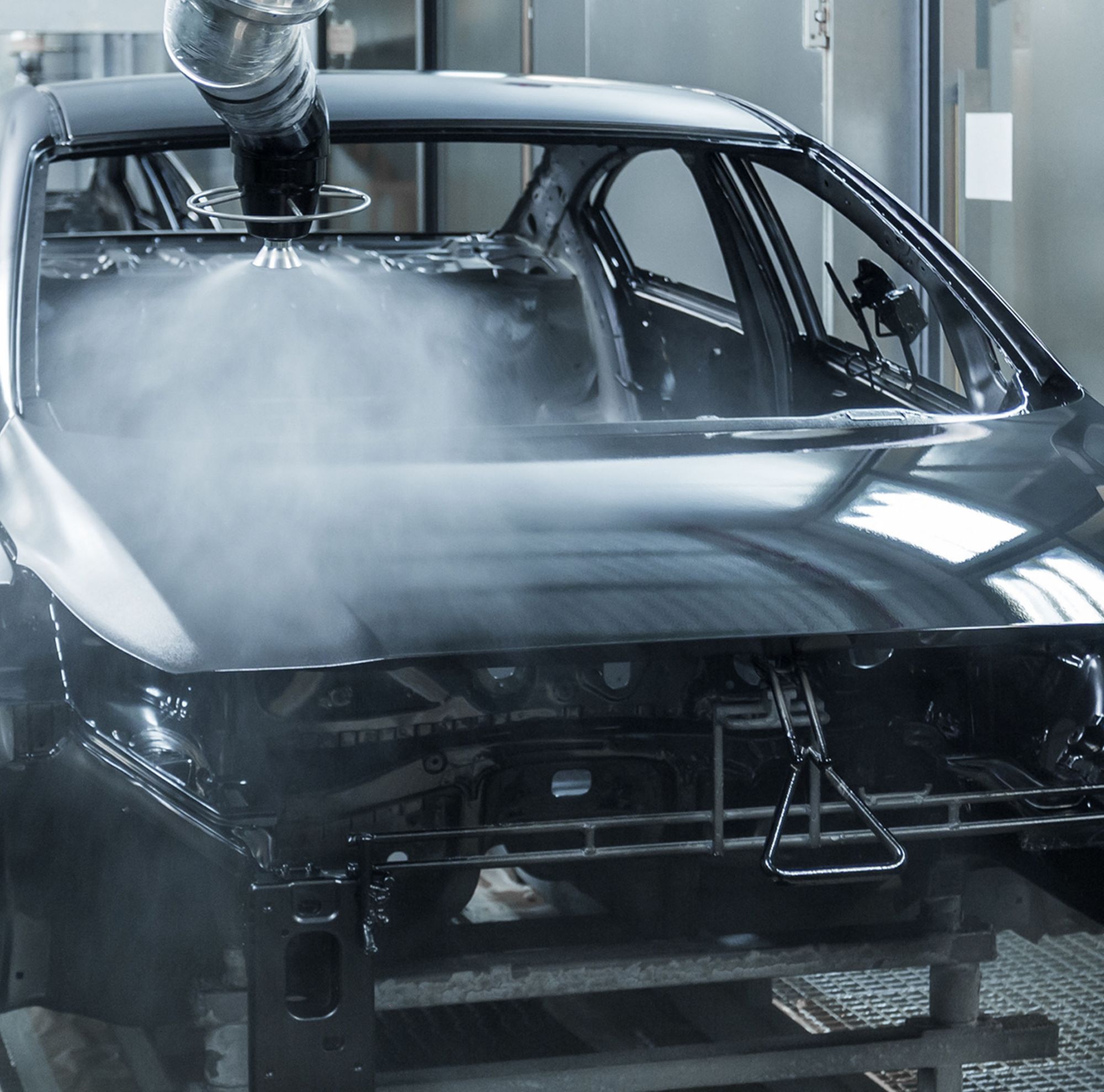 A machine applies paint to a car on a production line. 