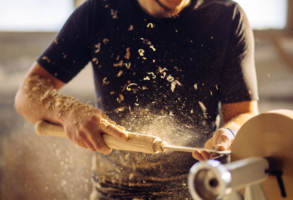 A carpenter using a spinning wood carving machine. 
