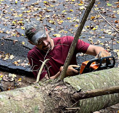 John Frady uses a chainsaw on a downed tree. 