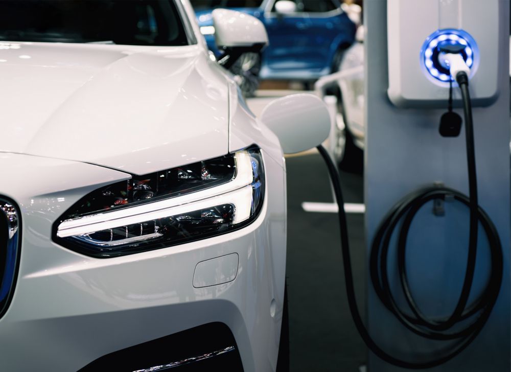 A white electric vehicle is charging while parked.  