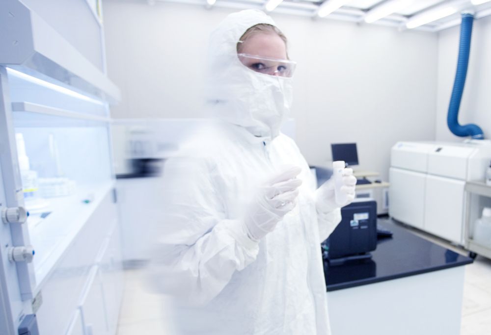 A scientist holds a vial in a clean room 