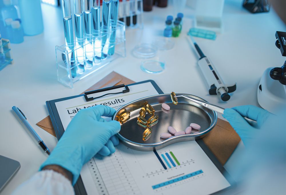 A gloved chemist uses tweezers to inspect an assortment of medications 
