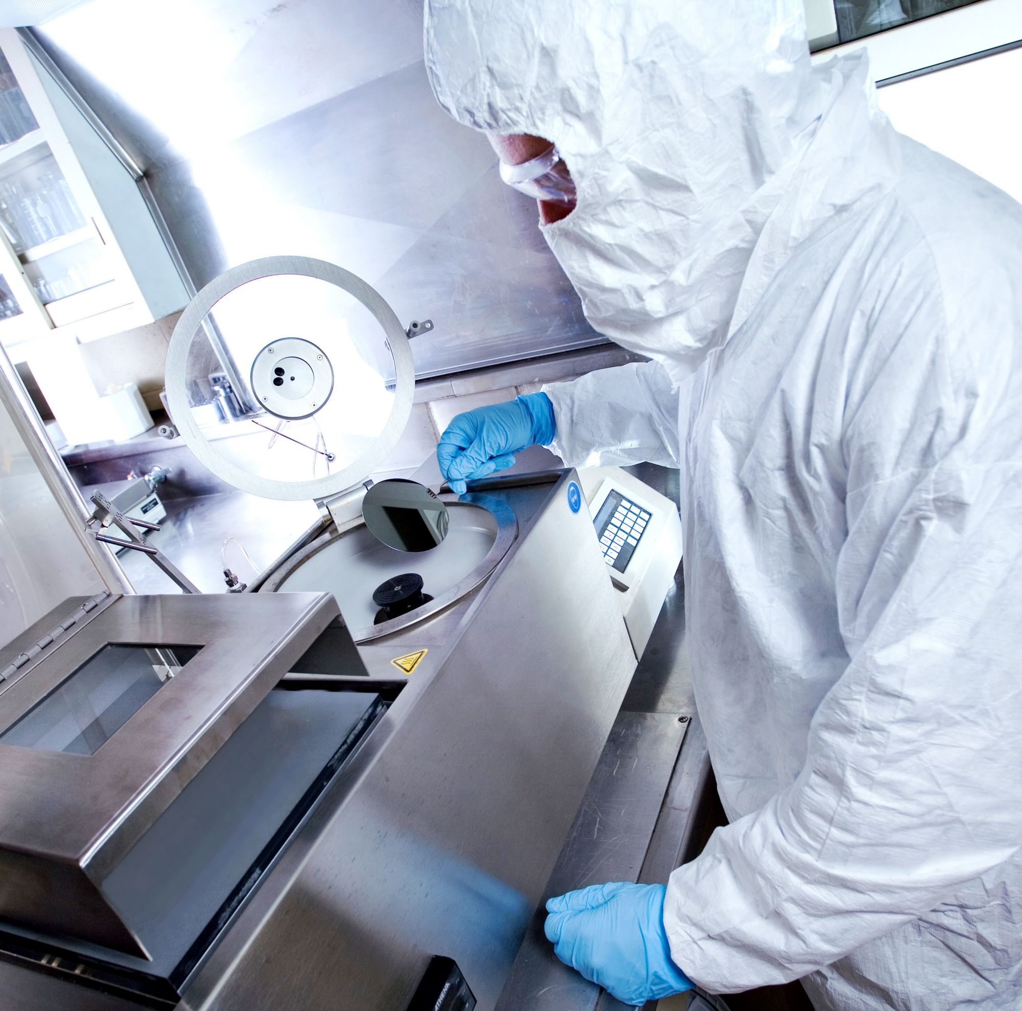 A technician looks at a product through a magnifying glass 