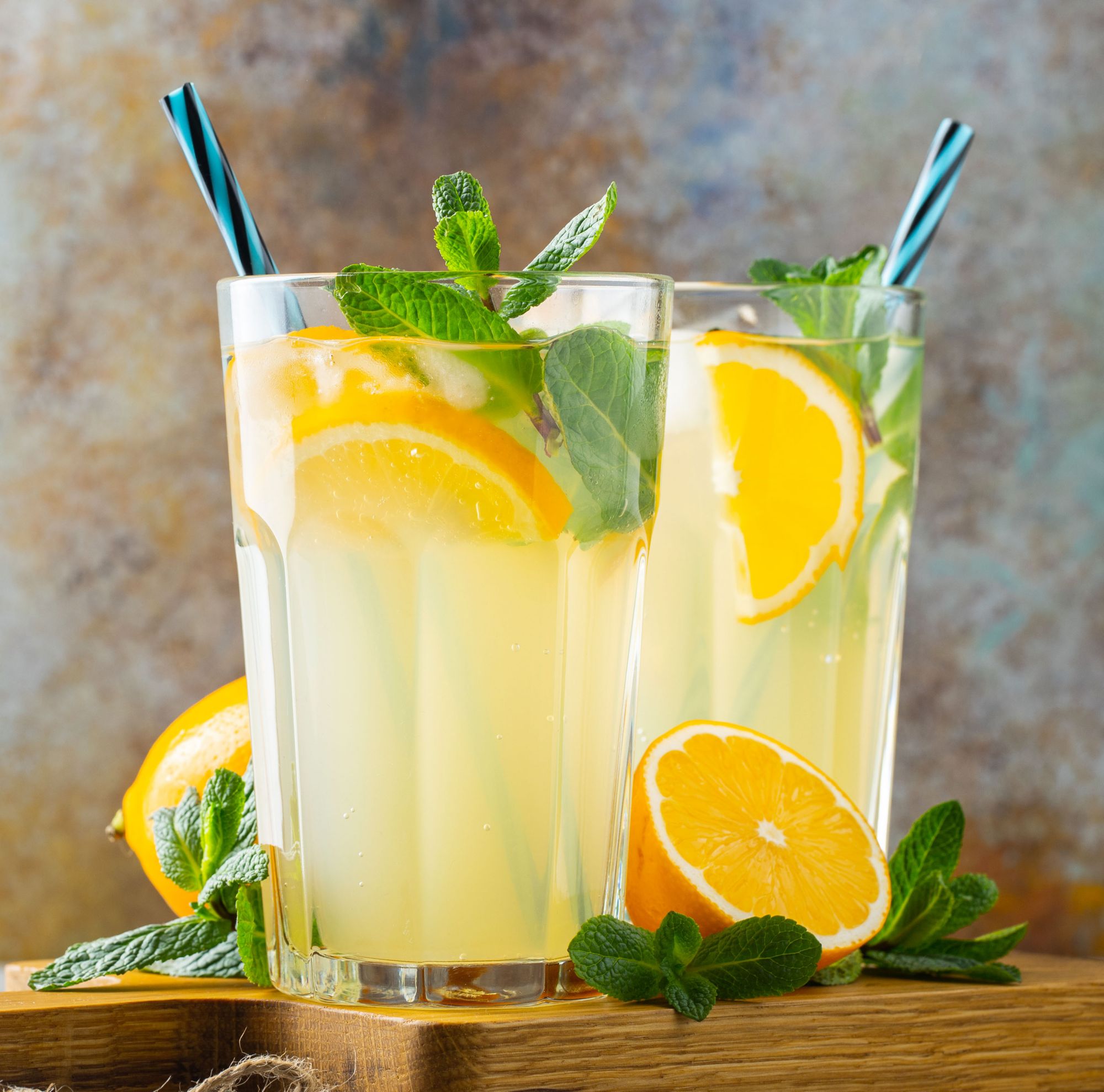 Two glasses of juice garnished with lemon and mint. 