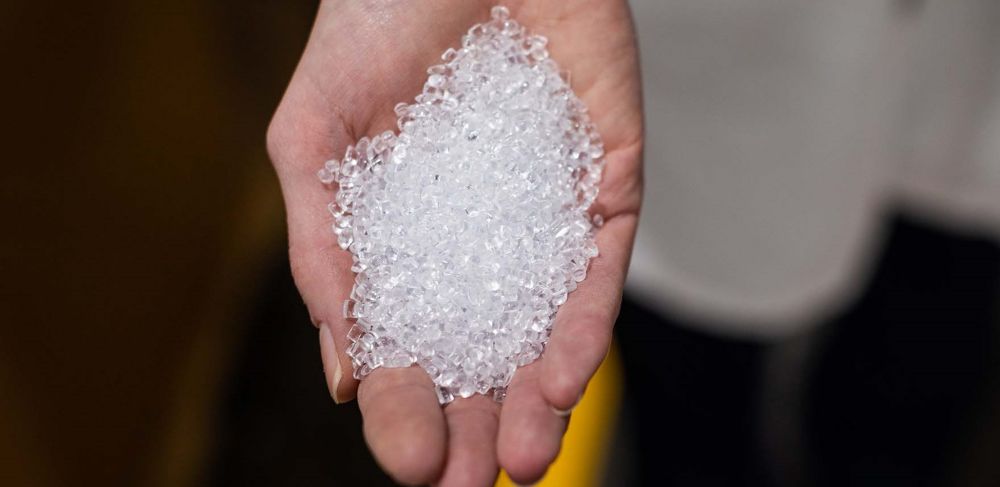 Clear pellets of recycled PET are in a person’s hand 