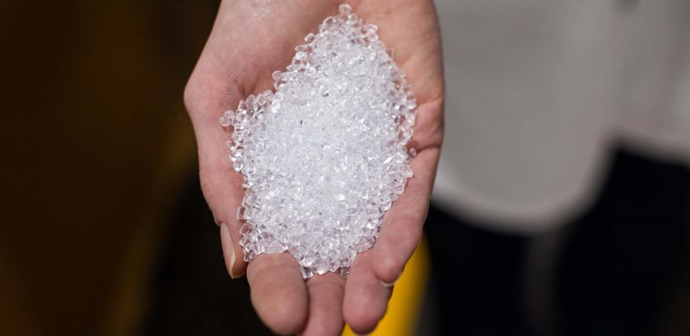 Clear pellets of recycled PET are in a person’s hand