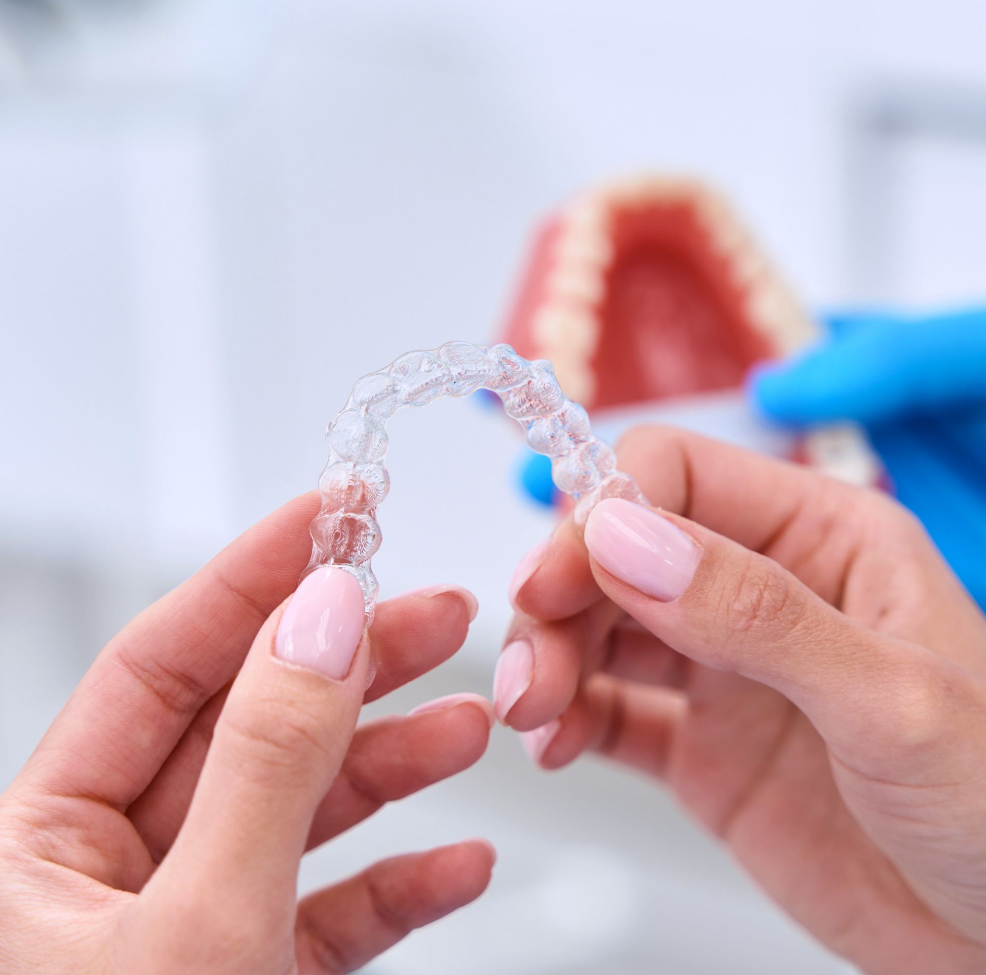 A person holding clear dental aligners. 