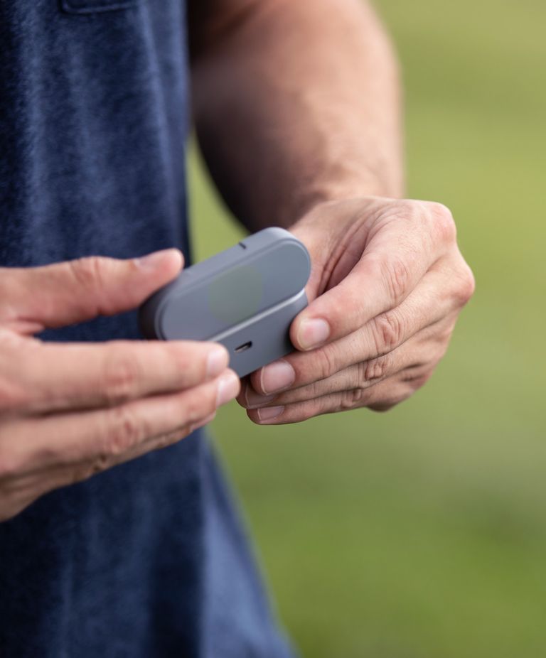 Close-up of person opening a Bluetooth earbud case. 