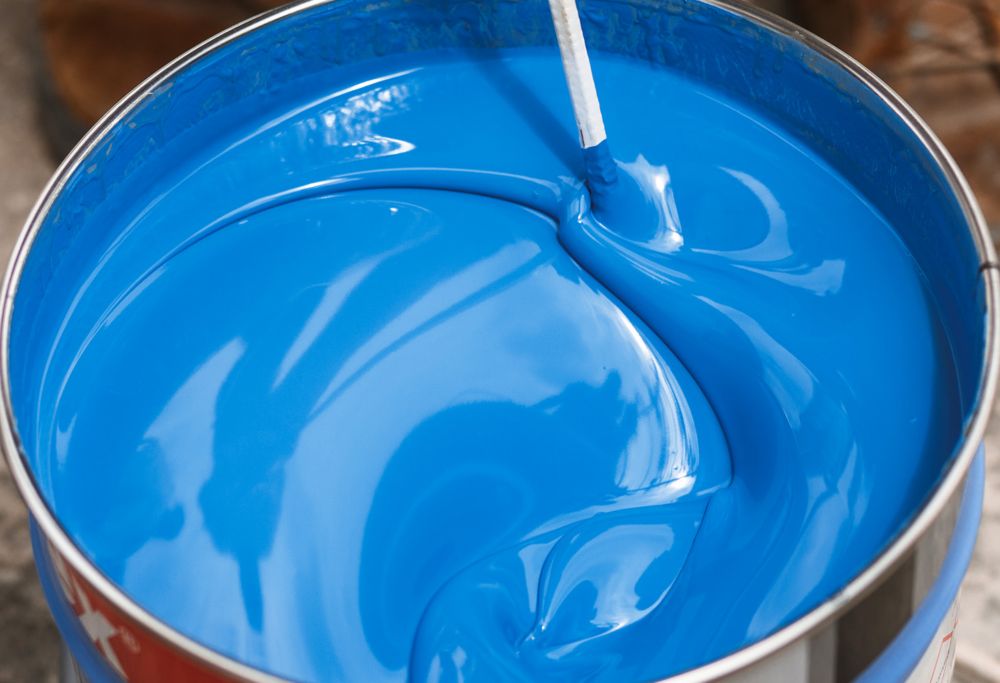 A swirl stick mixes a container of bright blue paint. 