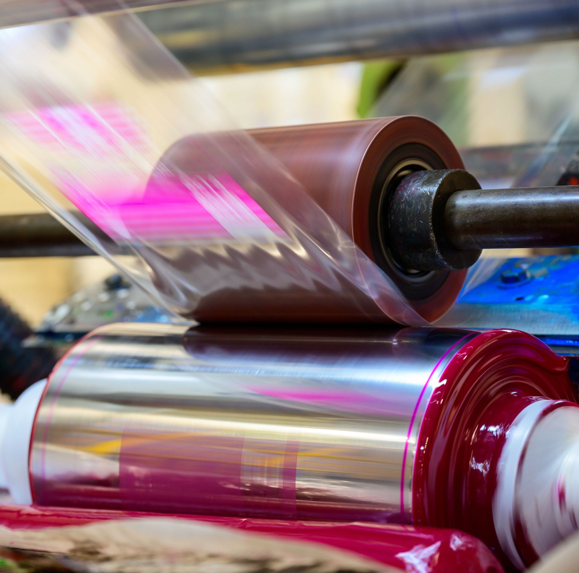 A roll of magenta-colored printing packaging coming off the press. 