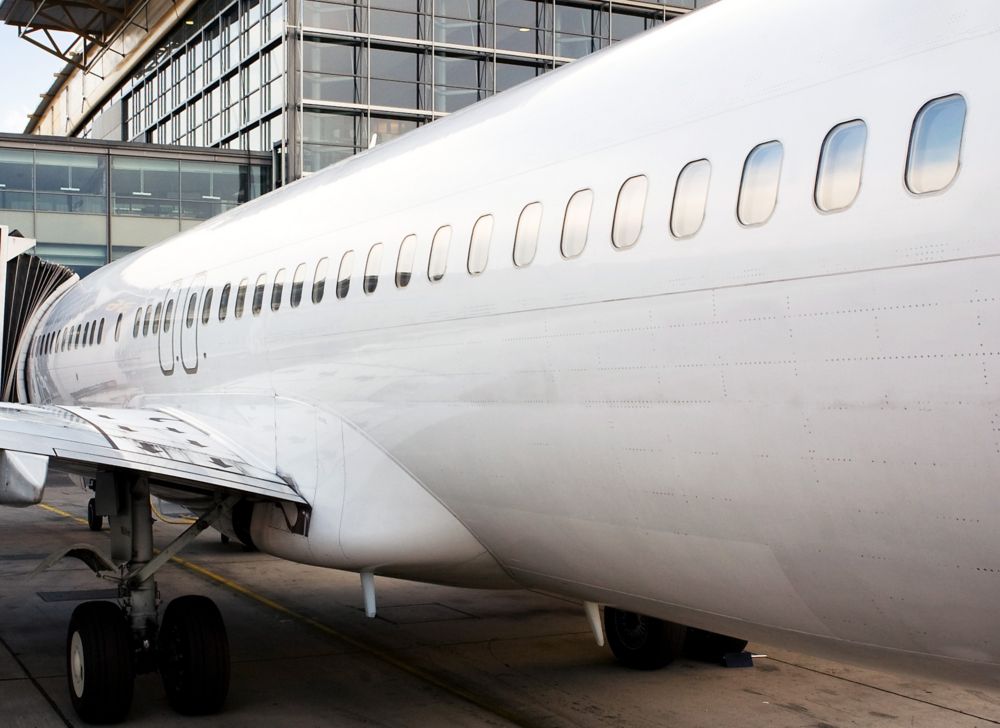 A parked white plane is seen from the front of the plane’s right side. 