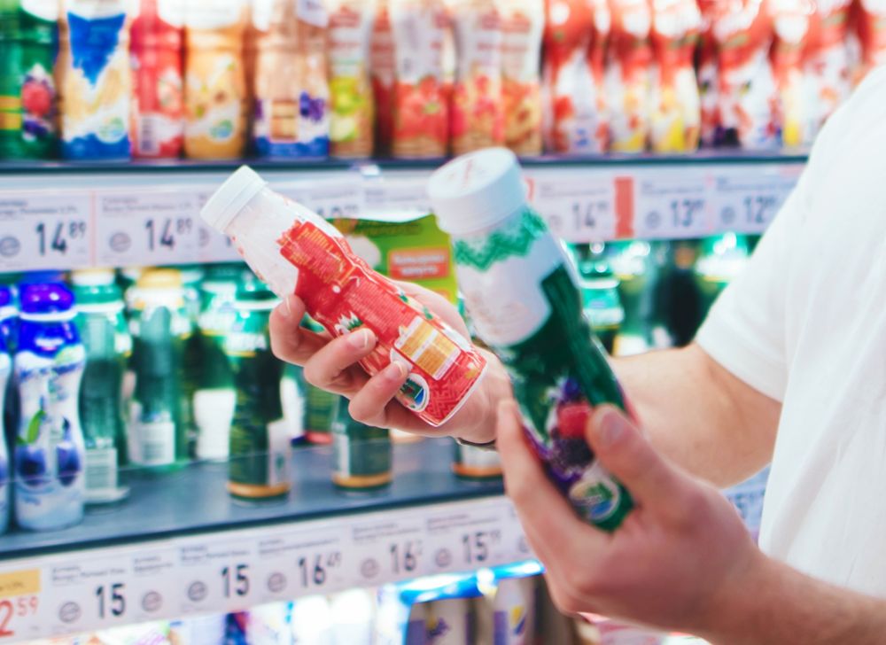 A person holds two different yogurt containers. 