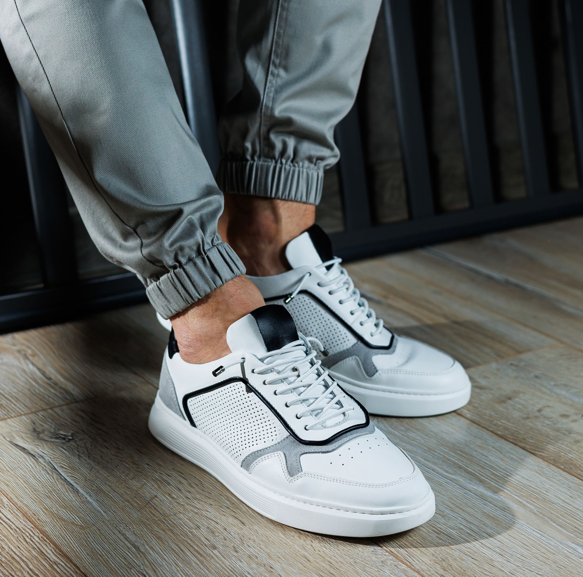 Closeup of person wearing white leather sneakers. 