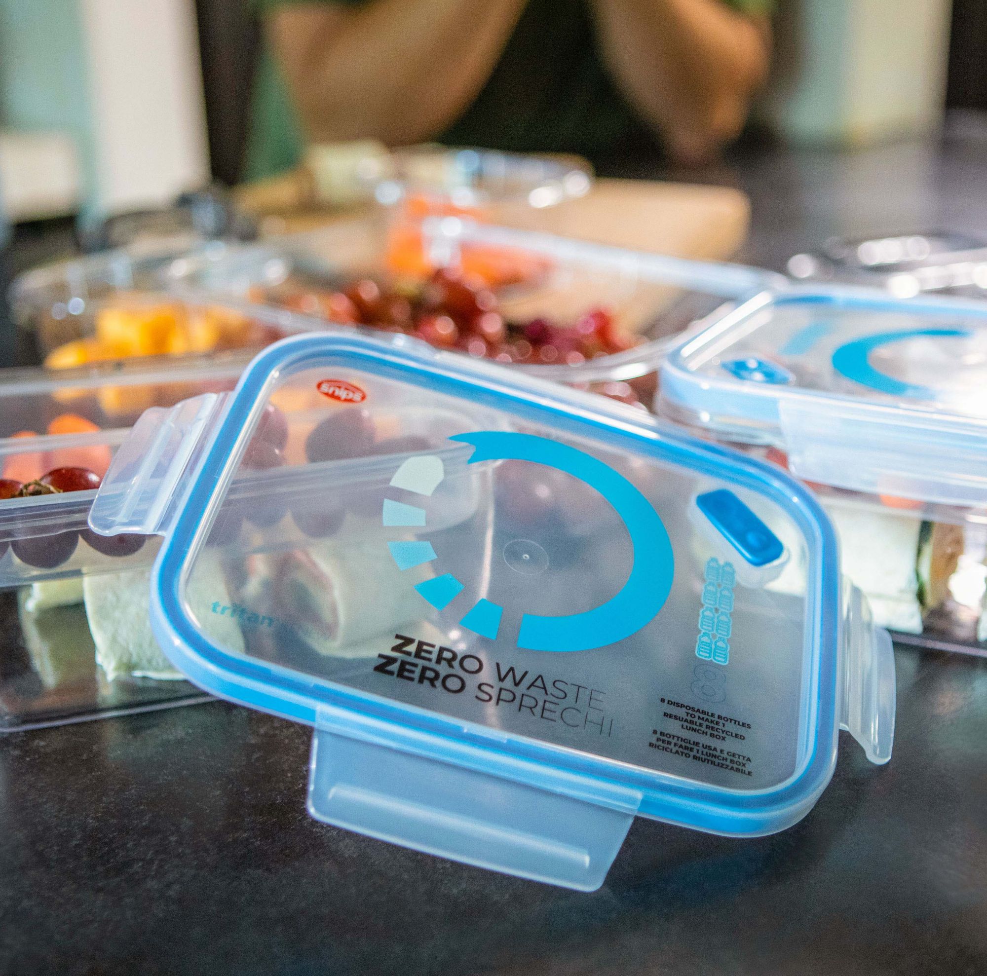 Several containers of food and lids sit on a surface. 