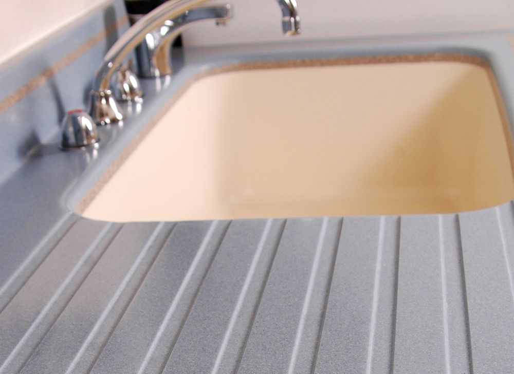An empty sink, with an empty gray countertop, is shown.  