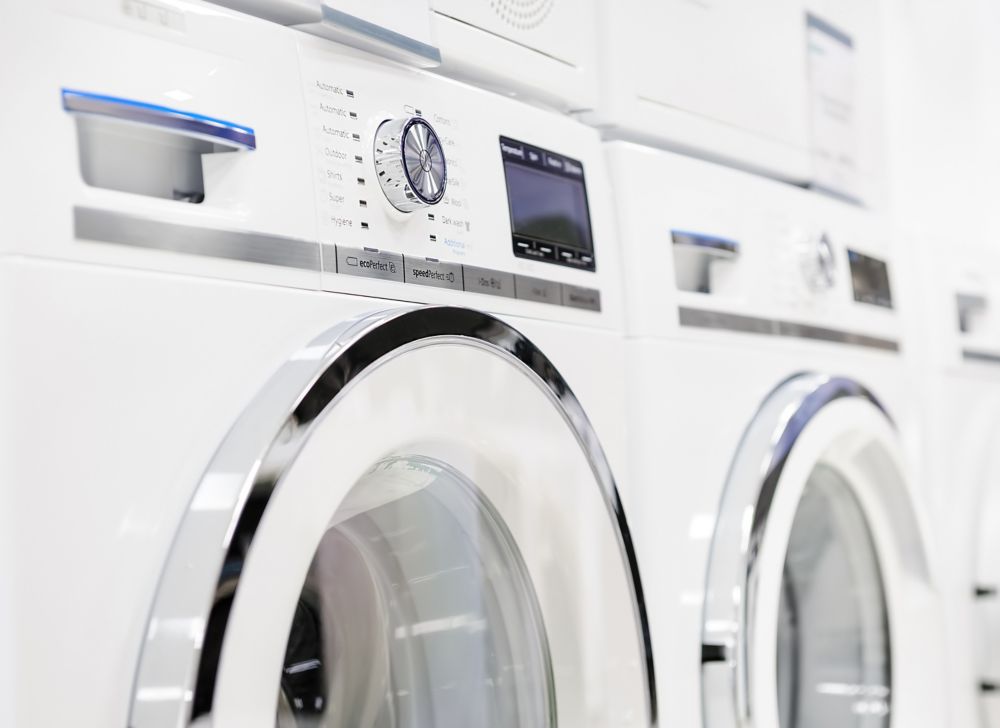 The top halves of three white washing machines are seen. 